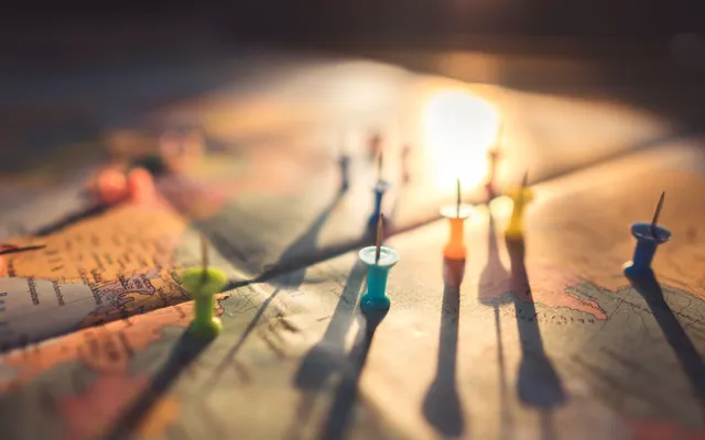 Coloured pins marking locations across a map, lit from one side
