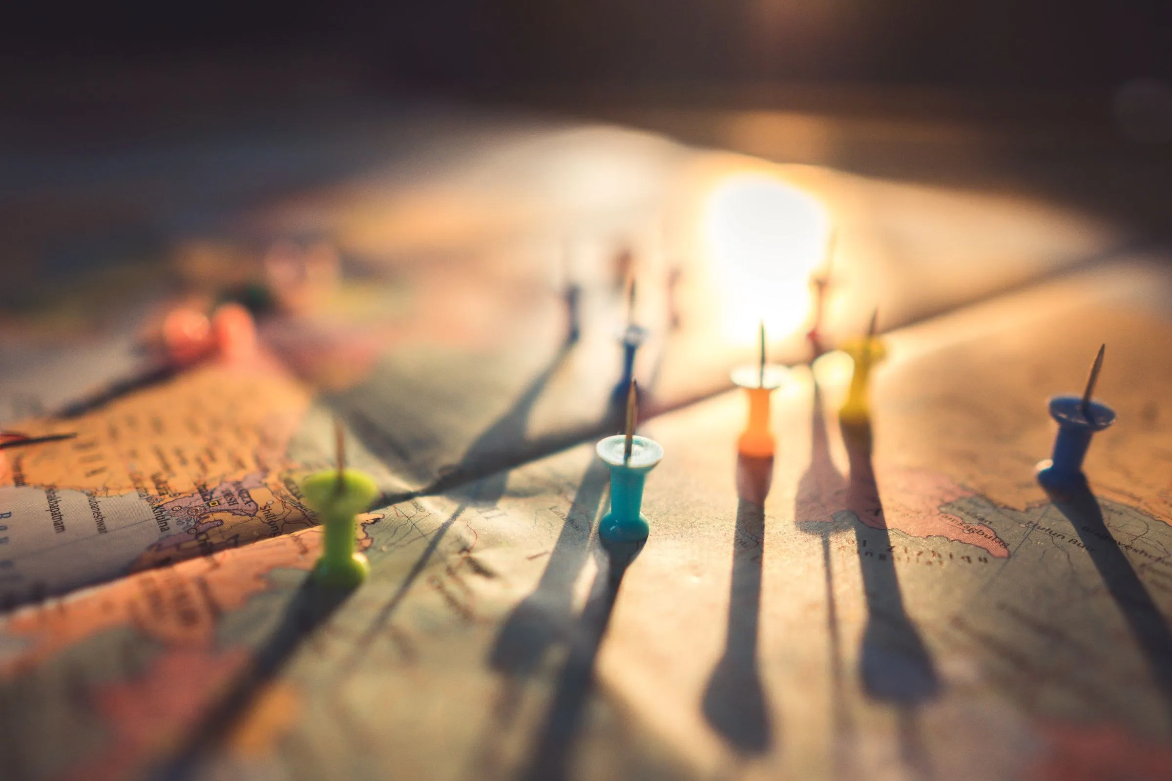 Coloured pins marking locations across a map, lit from one side